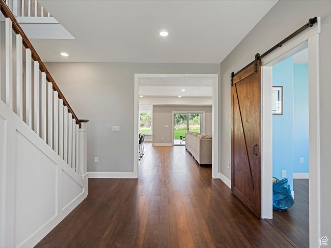 Entrance foyer with a barn door, dark wood-style floors, baseboards, stairs, and recessed lighting | Image 17