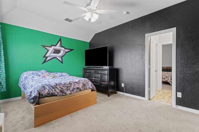 Carpeted bedroom featuring lofted ceiling, ceiling fan, a textured wall, and baseboards | Image 27