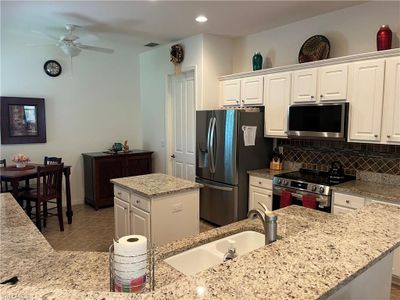 Kitchen with ceiling fan, white cabinets, a kitchen island with sink, and appliances with stainless steel finishes | Image 2