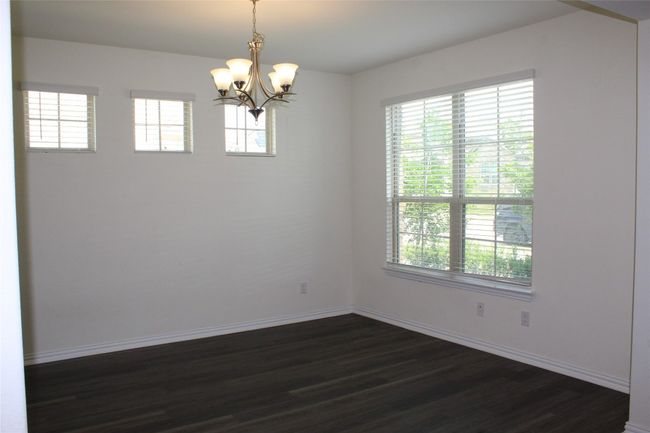 Empty room with a chandelier, dark wood-style floors, and healthy amount of natural light | Image 17