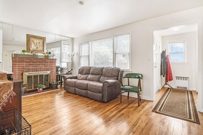 Living room with radiator, a wealth of natural light, and light wood finished floors | Image 7