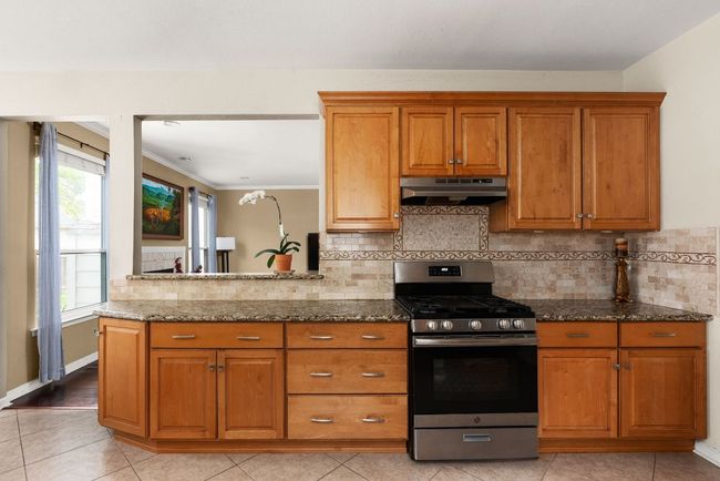 Kitchen with under cabinet range hood, brown cabinets, and stainless steel range with gas cooktop | Image 11