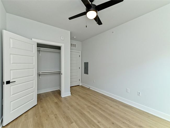 Unfurnished bedroom with light wood finished floors, electric panel, baseboards, and a closet | Image 10