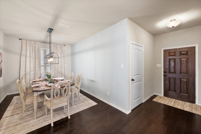 Dining room with a notable chandelier, dark wood-style floors, baseboards, and visible vents | Image 4