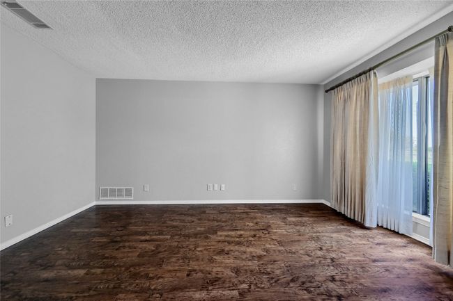 Unfurnished room with visible vents, a textured ceiling, and dark wood finished floors | Image 7