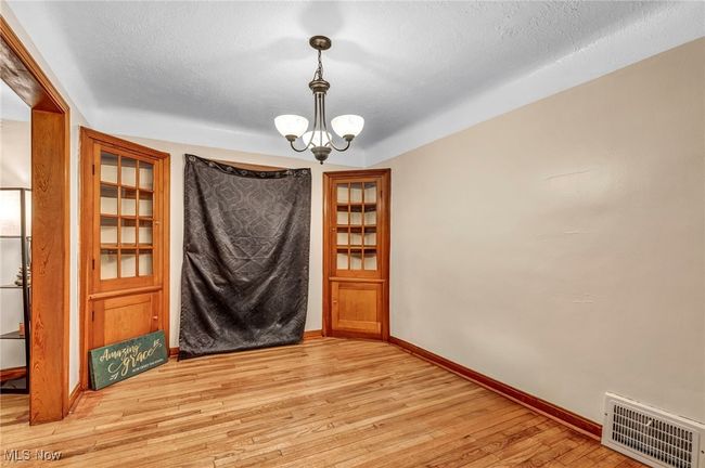 Unfurnished dining area with light wood-type flooring, baseboards, visible vents, and an inviting chandelier | Image 11