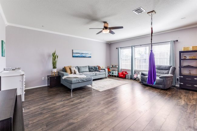 Living area with a ceiling fan, dark wood finished floors, crown molding, a textured ceiling, and baseboards | Image 8
