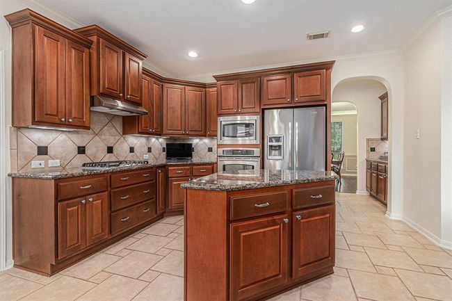 A spacious island kitchen awaits the chef of the home to prepare wonderful meals! This kitchen features warm stained cabinets, granite countertops and stainless steel appliances including a gas cooktop! | Image 12