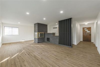 Unfurnished living room featuring wood-type flooring and a brick fireplace | Image 2