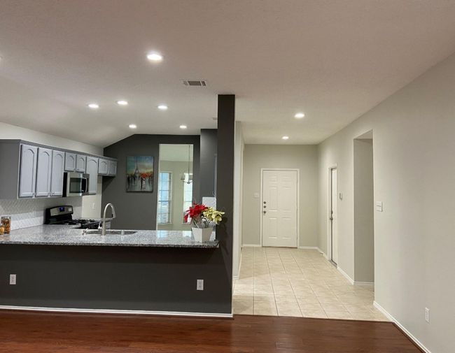 Kitchen featuring gray cabinetry, light stone countertops, recessed lighting, light wood finished floors, and appliances with stainless steel finishes | Image 5