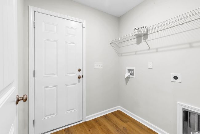 Laundry area featuring electric dryer hookup, washer hookup, wood finished floors, and baseboards | Image 27
