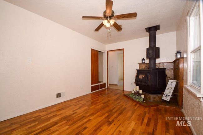 Living room with a wood stove, wood finished floors, and ceiling fan | Image 20