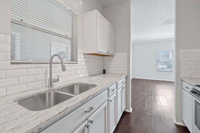 Kitchen featuring a textured ceiling, white cabinets, a sink, and dark wood-type flooring | Image 10