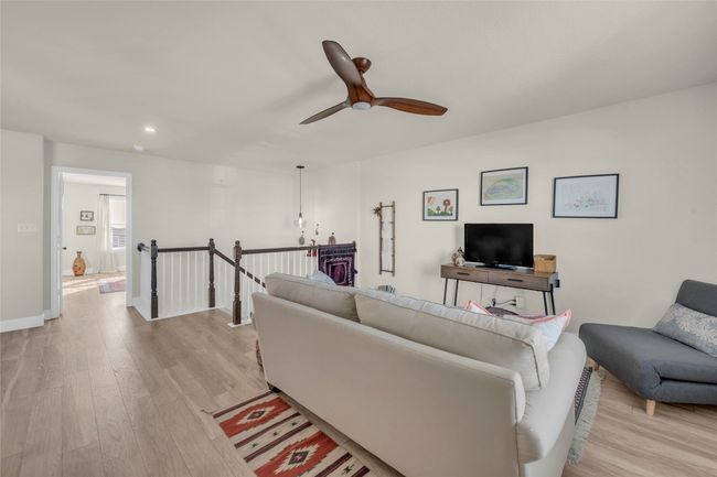 Loft space currently being used as a Living area featuring wood finished floors, recessed lighting, baseboards, and ceiling fan | Image 14