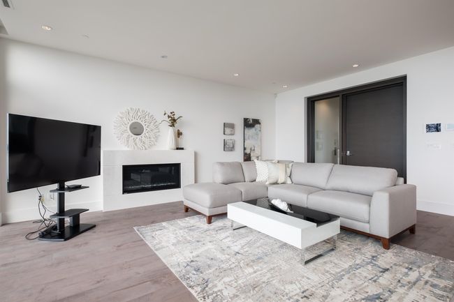 Living area with wood finished floors, recessed lighting, and a glass covered fireplace | Image 7