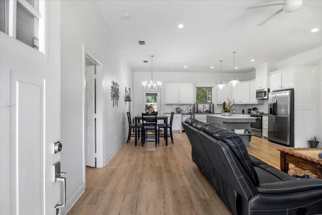 Living room featuring light wood-type flooring, recessed lighting, and ceiling fan with notable chandelier | Image 6