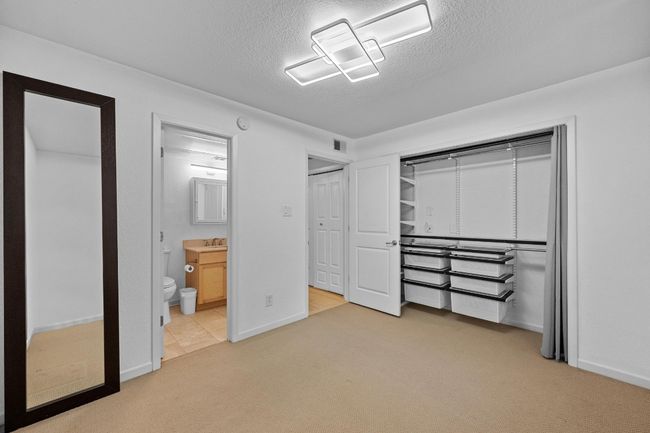 Unfurnished bedroom with carpet floors, a textured ceiling, a sink, baseboards, and connected bathroom | Image 8