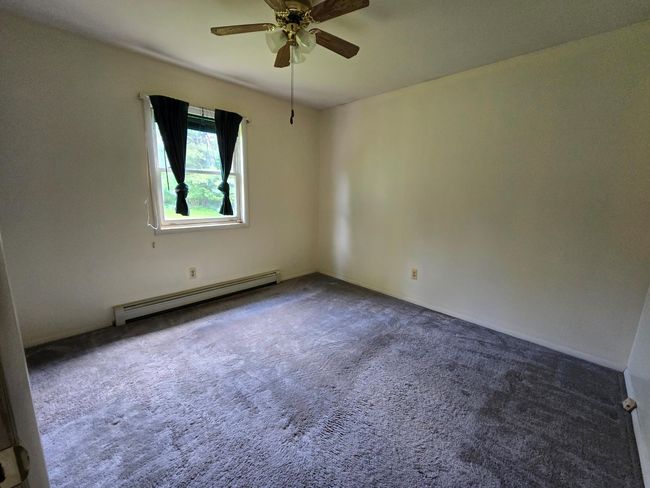 Carpeted spare room featuring a baseboard radiator and a ceiling fan | Image 5