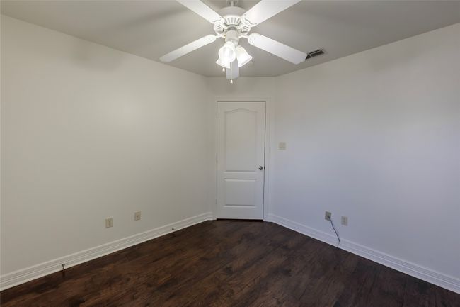 Spare room with dark wood finished floors, visible vents, baseboards, and ceiling fan | Image 32