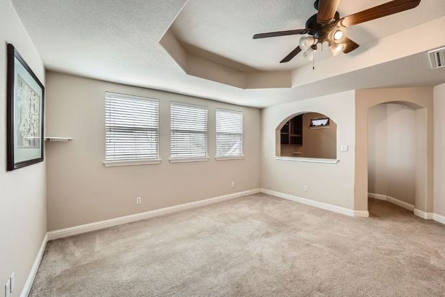 Unfurnished room featuring carpet floors, a ceiling fan, baseboards, and a tray ceiling | Image 33