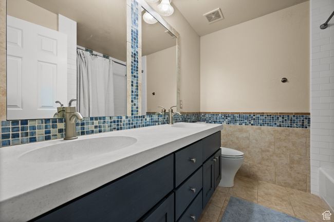 Bathroom featuring tile walls, toilet, and a sink | Image 17