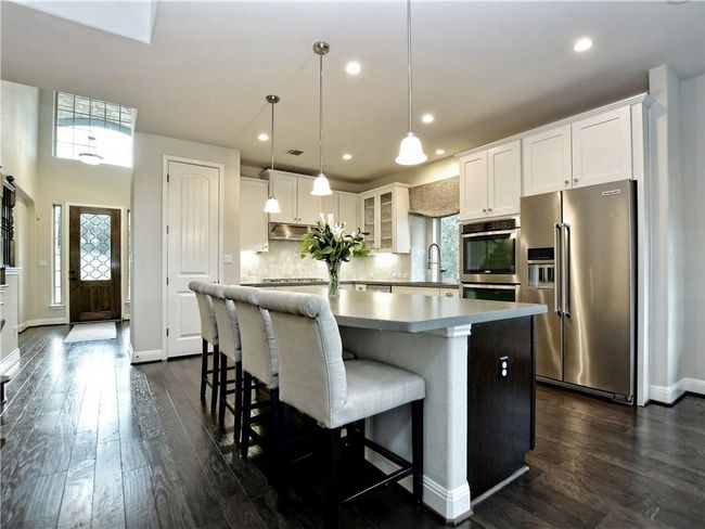 Kitchen featuring appliances with stainless steel finishes, a kitchen island, dark wood finished floors, white cabinets, and decorative backsplash | Image 18