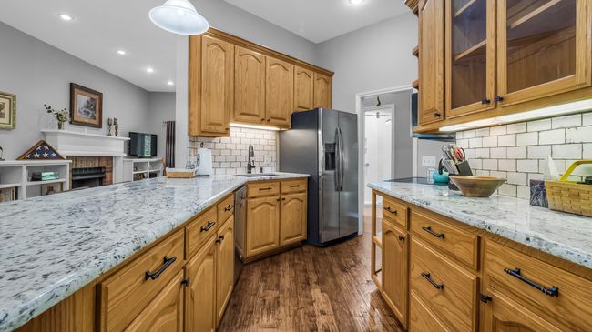 Kitchen featuring appliances with stainless steel finishes, a sink, glass insert cabinets, and light stone counters | Image 5