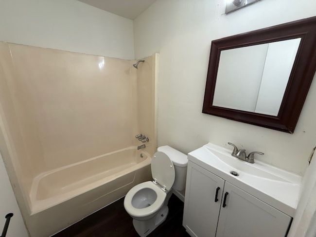 Bathroom with toilet, washtub / shower combination, vanity, and wood finished floors | Image 10