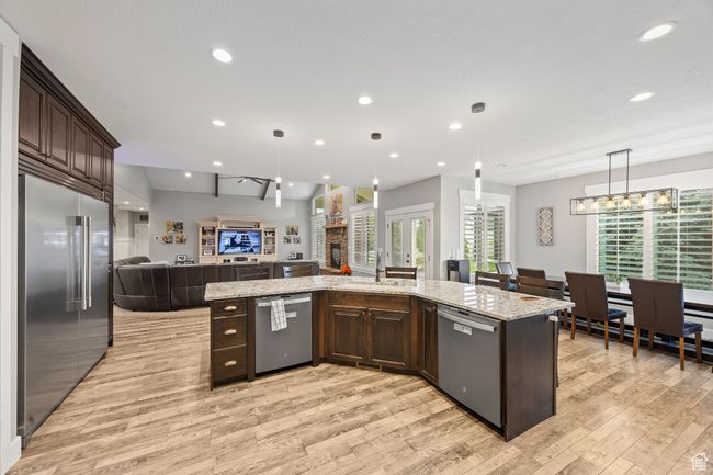 Kitchen with stainless steel appliances, two dishwashers, open floor plan, dark brown cabinets, light wood-style floors, and recessed lighting | Image 13