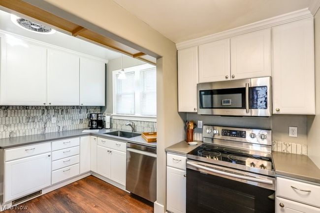 Kitchen with decorative backsplash, stainless steel appliances, visible vents, and a stainless steel sink | Image 16