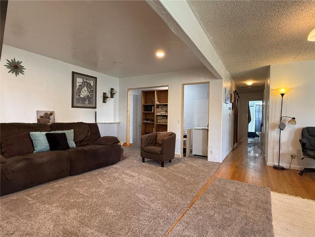 Living room with wood finished floors, baseboards, and a textured ceiling | Image 6