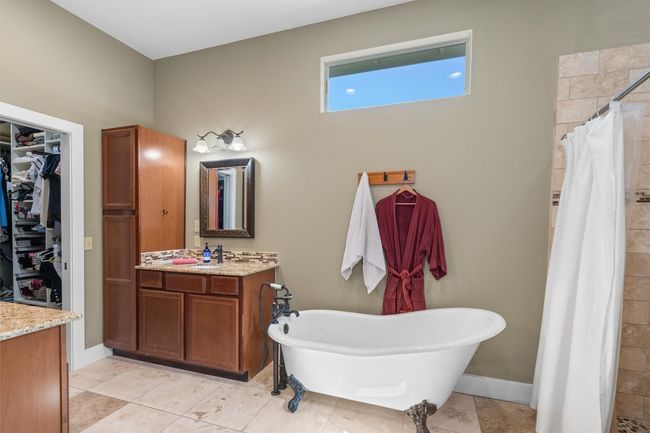 Bathroom featuring vanity, a walk in closet, a tile shower, baseboards, and a soaking tub | Image 15