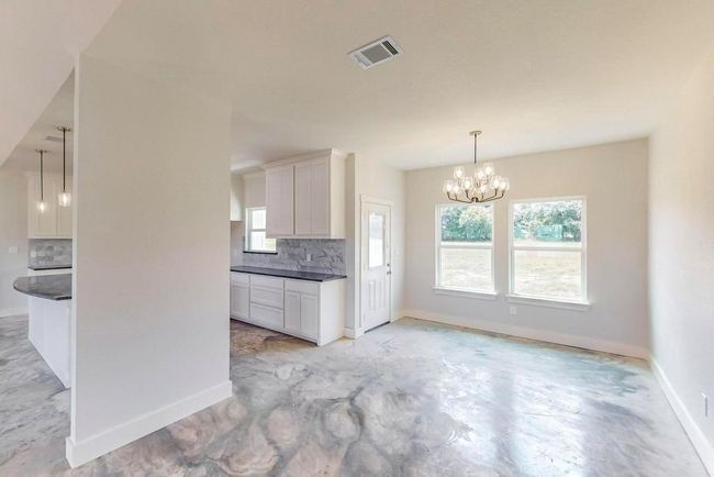 Kitchen featuring decorative backsplash, dark countertops, and white cabinetry | Image 9