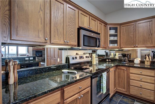 Mirrored backsplash provides a dramatic effect against the stylish granite. Loads of storage, including drawers and display cabinet. | Image 25