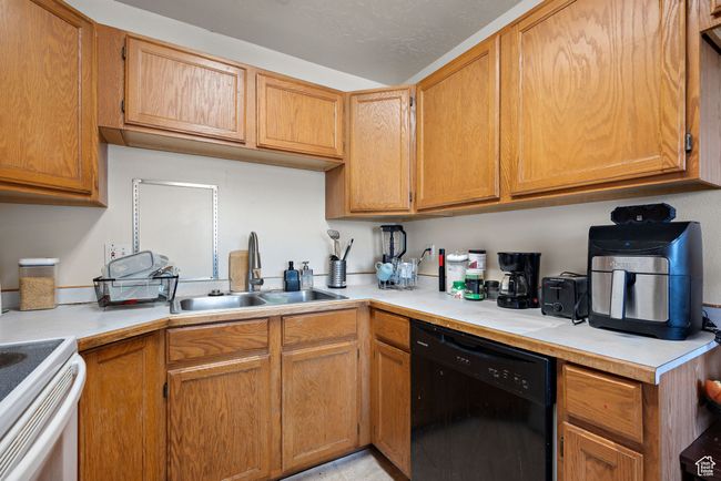 Kitchen featuring black dishwasher, light countertops, and white electric range oven | Image 39