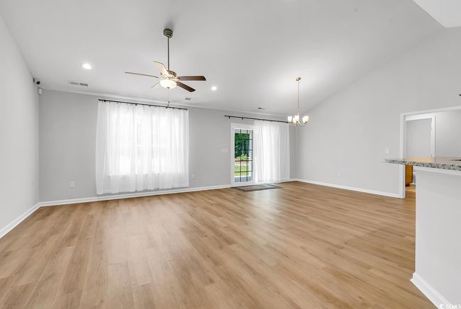 Unfurnished living room featuring ceiling fan, light wood-style flooring, a chandelier, baseboards, and recessed lighting | Image 4