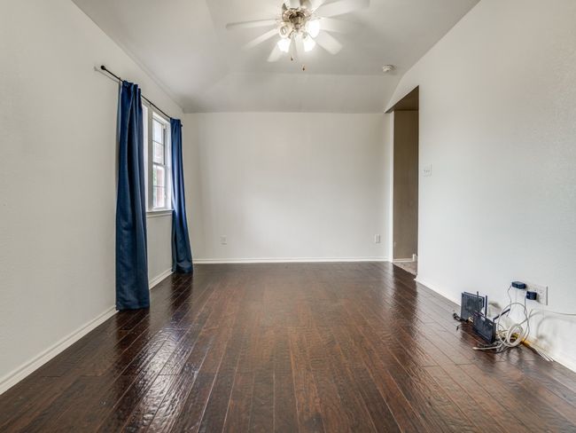 Empty room featuring baseboards, hardwood / wood-style flooring, a ceiling fan, and vaulted ceiling | Image 15