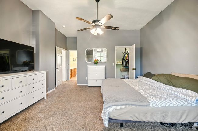 Bedroom featuring light colored carpet, a walk in closet, baseboards, a closet, and connected bathroom | Image 13