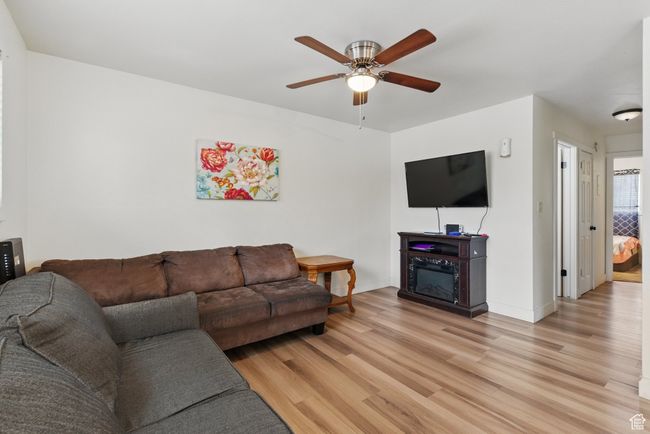 Living room with light wood-style floors, baseboards, and ceiling fan | Image 14