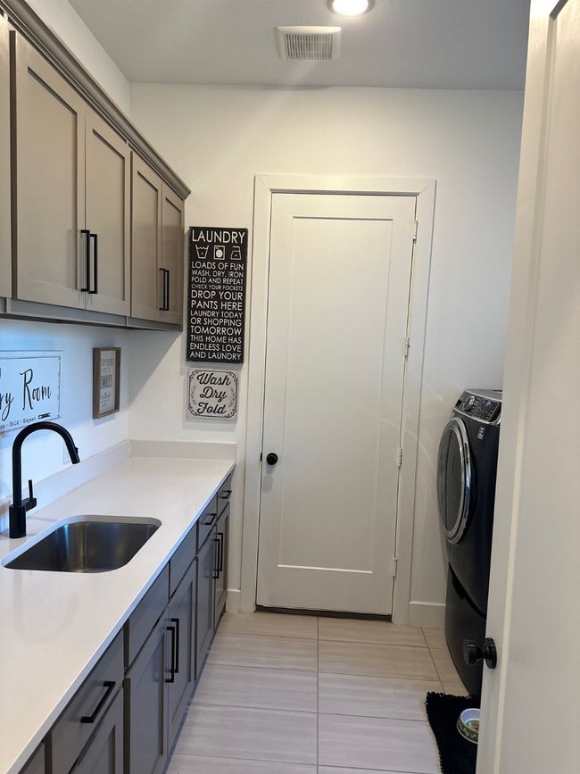 Washroom featuring cabinet space, light tile patterned floors, visible vents, washer / clothes dryer, and a sink | Image 31