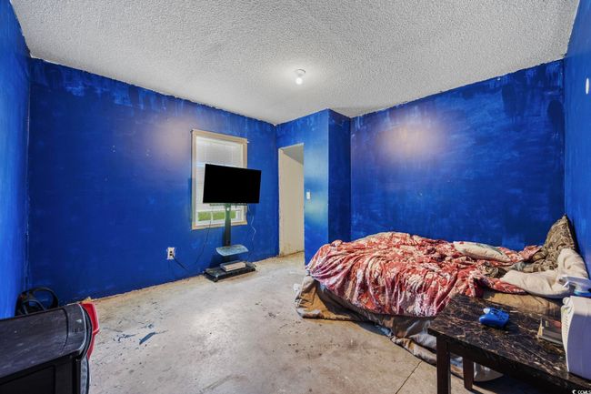 Bedroom with a textured ceiling and concrete flooring | Image 17