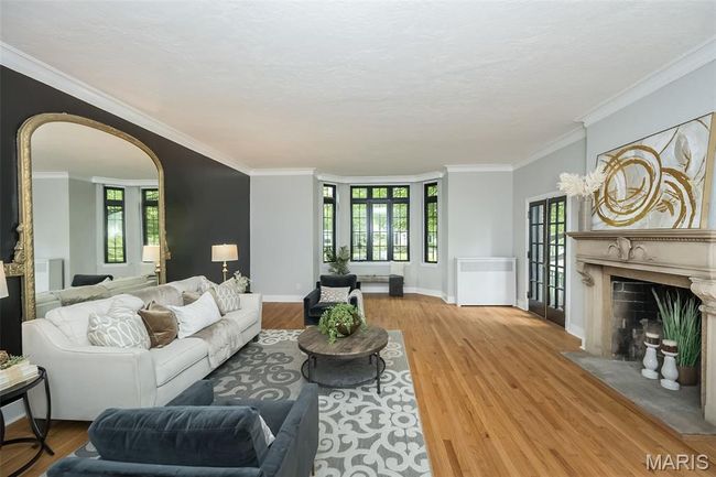 Living area with a high end fireplace, arched walkways, light wood-style flooring, plenty of natural light, and ornamental molding | Image 6