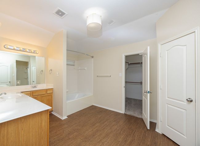 Master Bathroom featuring wood finished floors, vanity, bathtub / shower combination, and a spacious closet | Image 23