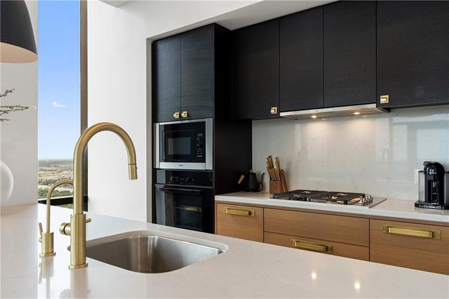 Kitchen featuring oven, a sink, dark cabinetry, stainless steel gas stovetop, and built in microwave | Image 12