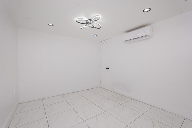 Empty room featuring a wall unit AC, light marble finish floors, and recessed lighting | Image 12