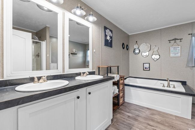Full bath featuring double vanity, a bath, wood finished floors, a shower stall, and crown molding | Image 17