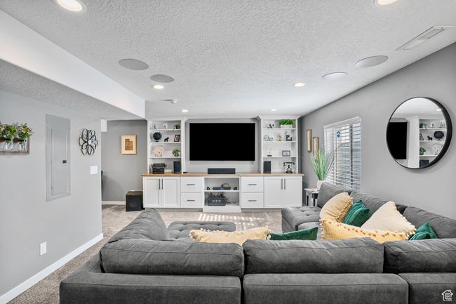 Living room with light colored carpet, baseboards, a textured ceiling, and electric panel | Image 5