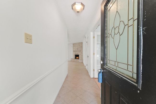 Welcome to your new home! This inviting entryway features a charming stained glass door, leading into a bright hallway with a cozy fireplace visible in the living area. Perfect for creating a warm and welcoming atmosphere. | Image 5