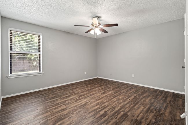 Empty room featuring a ceiling fan, dark wood finished floors, a textured ceiling, and baseboards | Image 19
