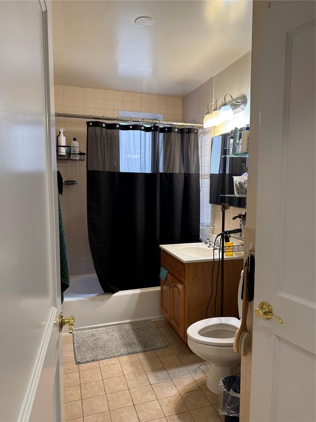 Full bathroom featuring toilet, shower / tub combo, vanity, and tile patterned floors | Image 5